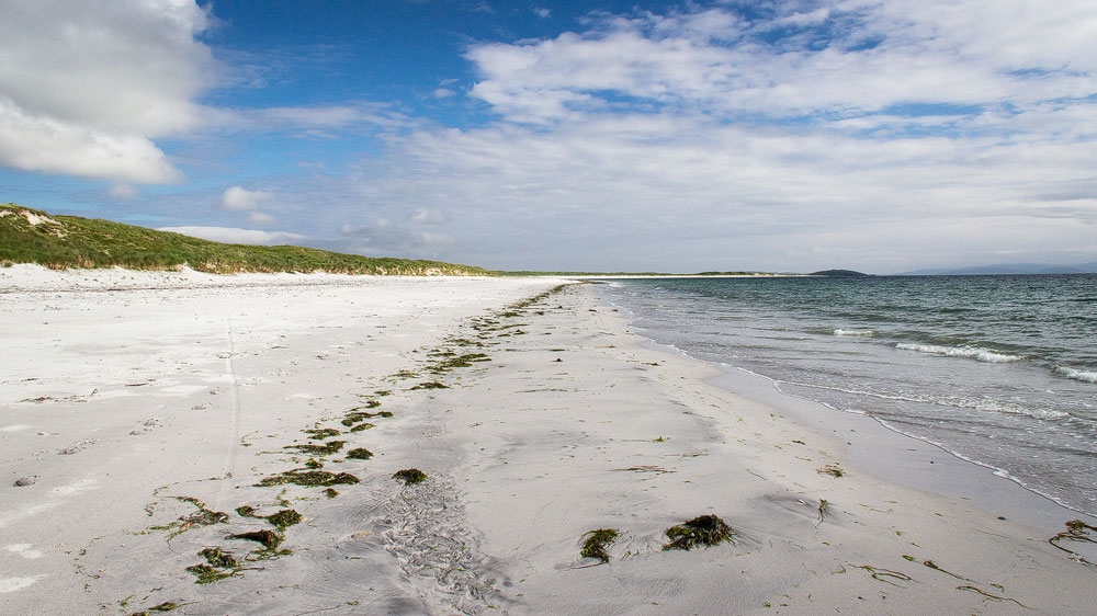 Ein sehr langer Sandstrand mit blauem Himmel darüber