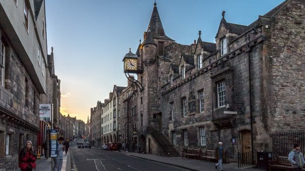 Die Canongate Tolbooth in der Royal Mile ist ein graubraunes Steingebäude mit einem kleinen Turm und einer daran befestigten auffälligen Uhr.