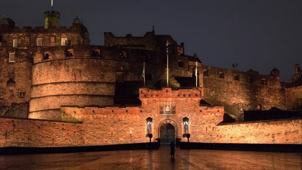 Nachts und bei Regen vor dem Tor der Edinburgh Castle. Der Eingang und die Mauern sind beleuchtet.