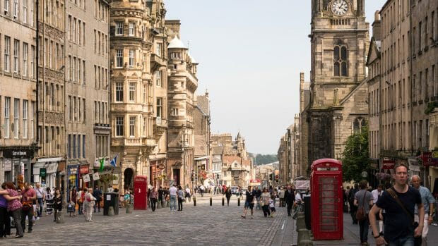 Ein Blick die Einkaufsstraße Royal Mile hinab. Es sind Menschen zu sehen und zwei typische rote Telefonhäuschen.