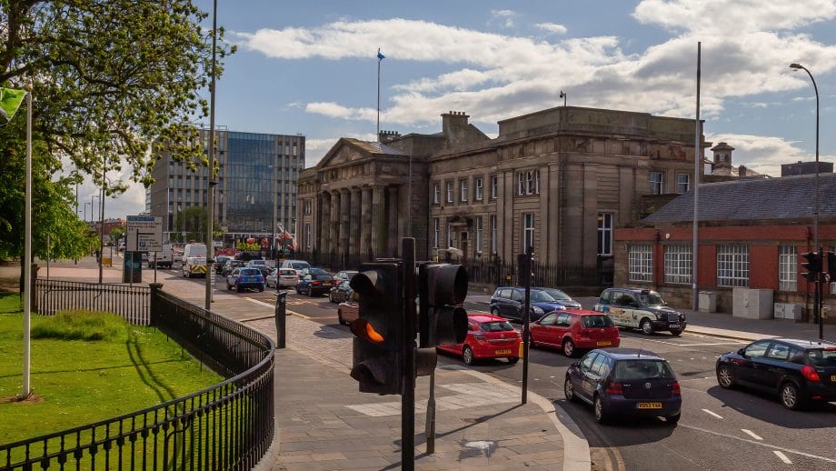 Eine Straße mit vielen Autos führt auf das Glasgow Justizgebäude zu.