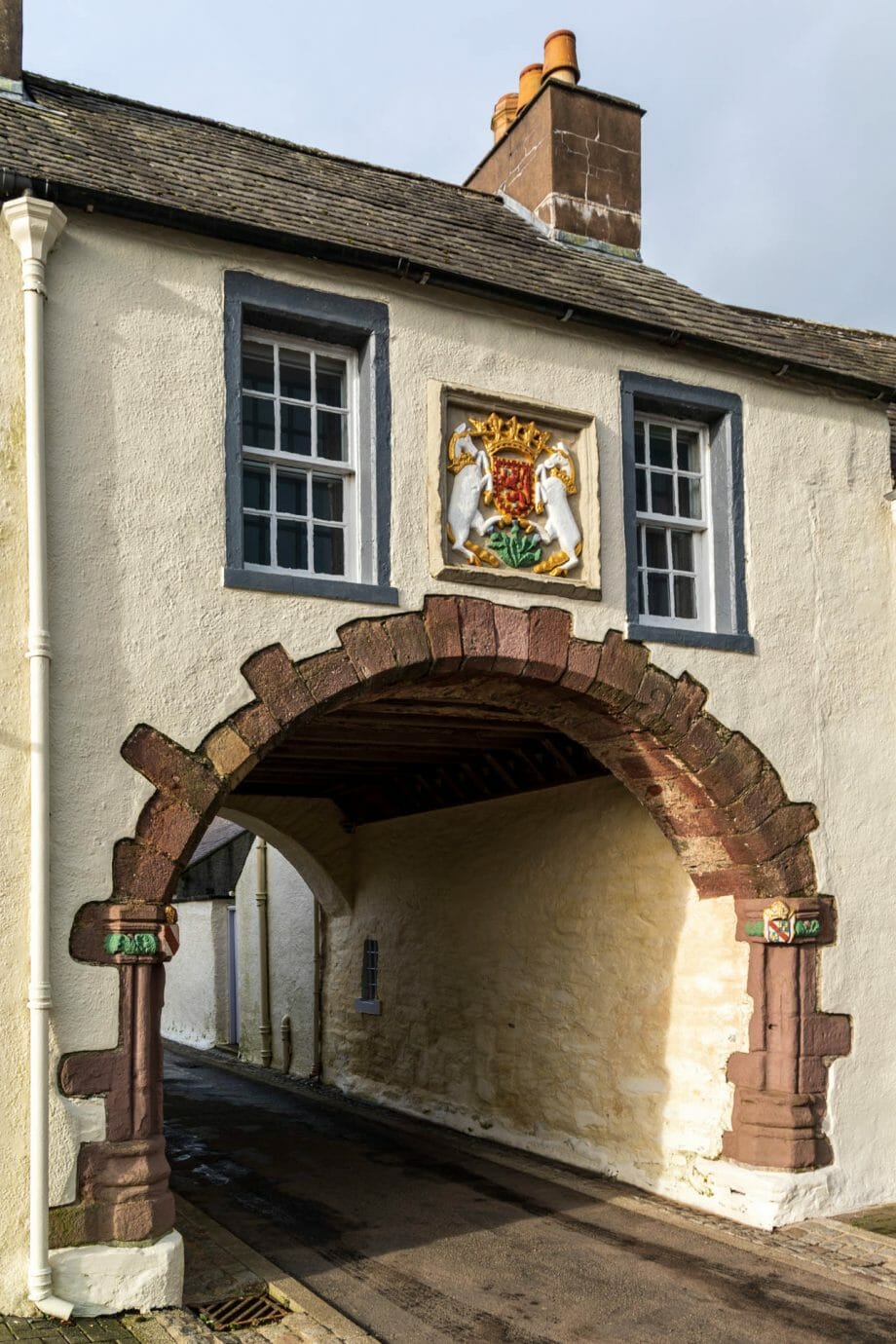 Ein Tor in einem weißen Gebäude. Darüber das schottische Wappen. 