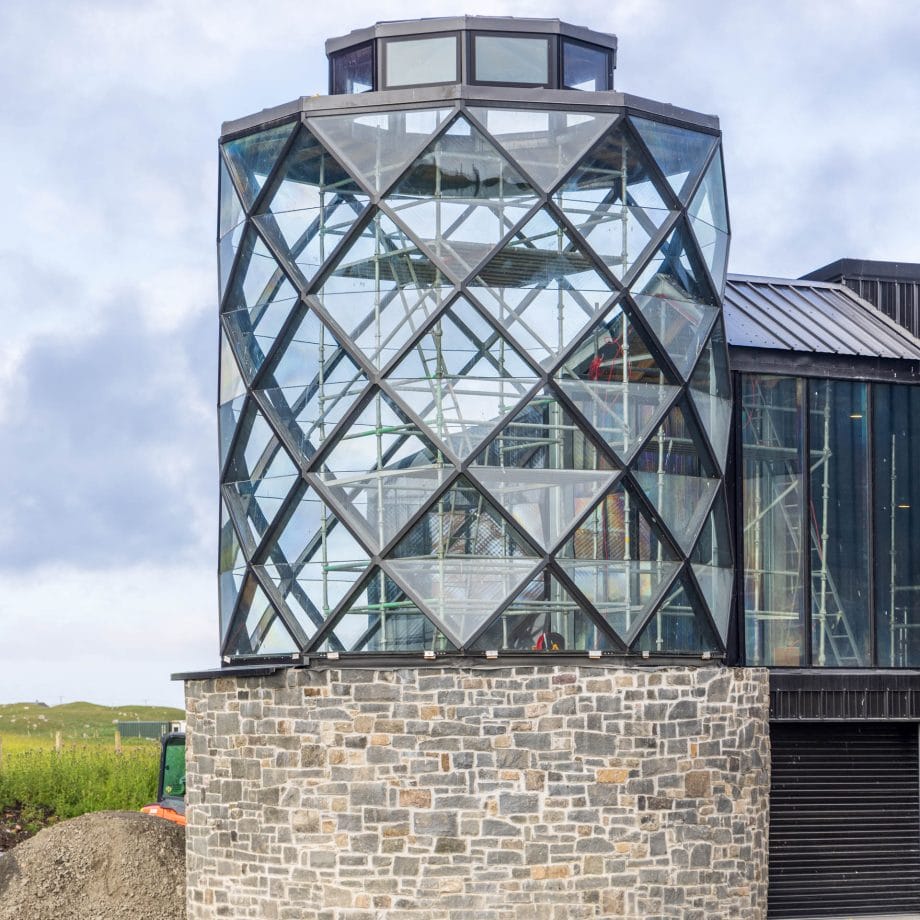 Ein Turm aus Metall und Glas auf einem runden Steinsockel