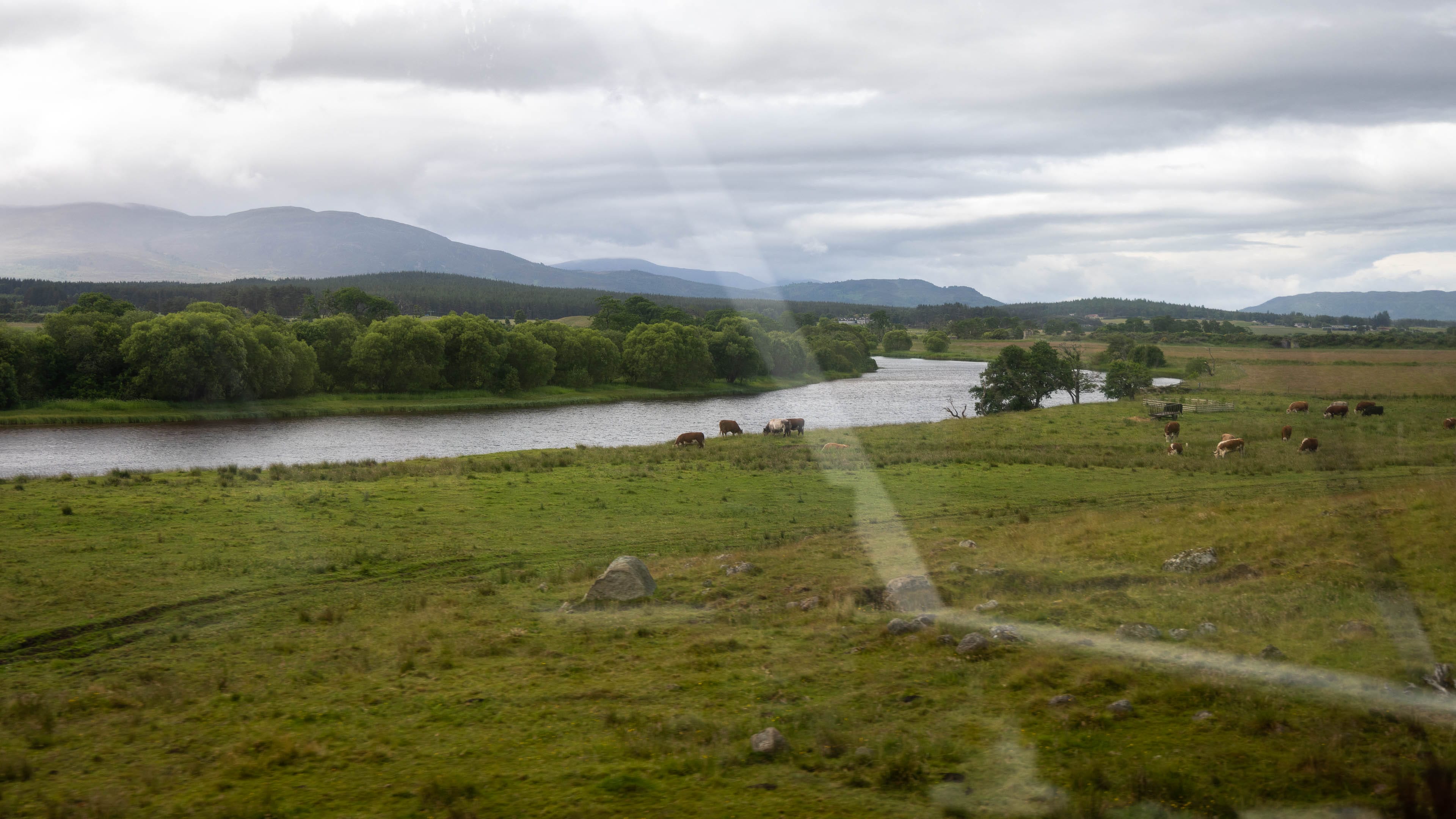 Ein Blick aus dem Aussichtswaggon der Strathspey Railway auf den Fluss Spey mit den Cairngorms dahinter.