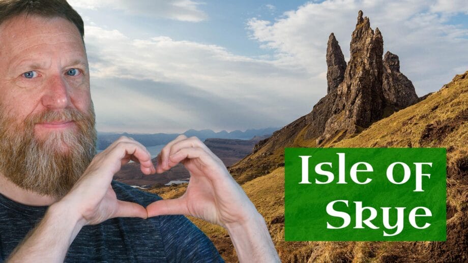 Ein Mann formt mit seinen Händen ein Herzchen, im Hinterrgund ist der Old Man of Storr auf der isle of Skye zu sehen.