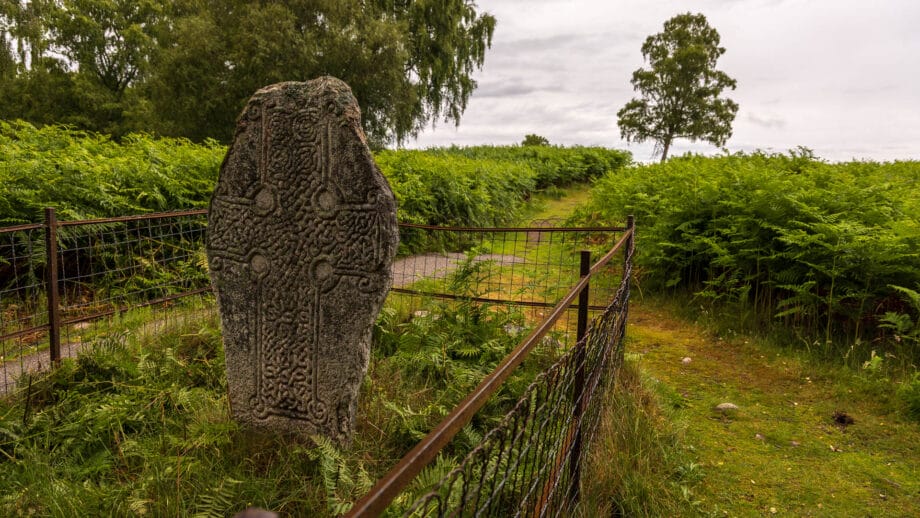 Ein Stein mit kunstvoller Steinmetzarbeit aus der Zeit der Pikten steht in einer grünen Landschaft